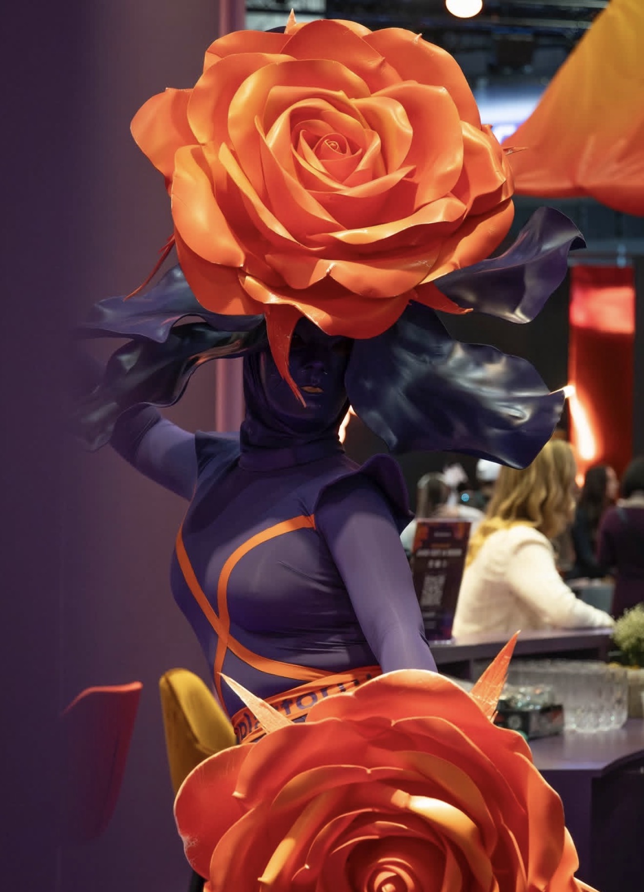 Performer con vestuario morado y grandes flores naranjas: ICE Barcelona.