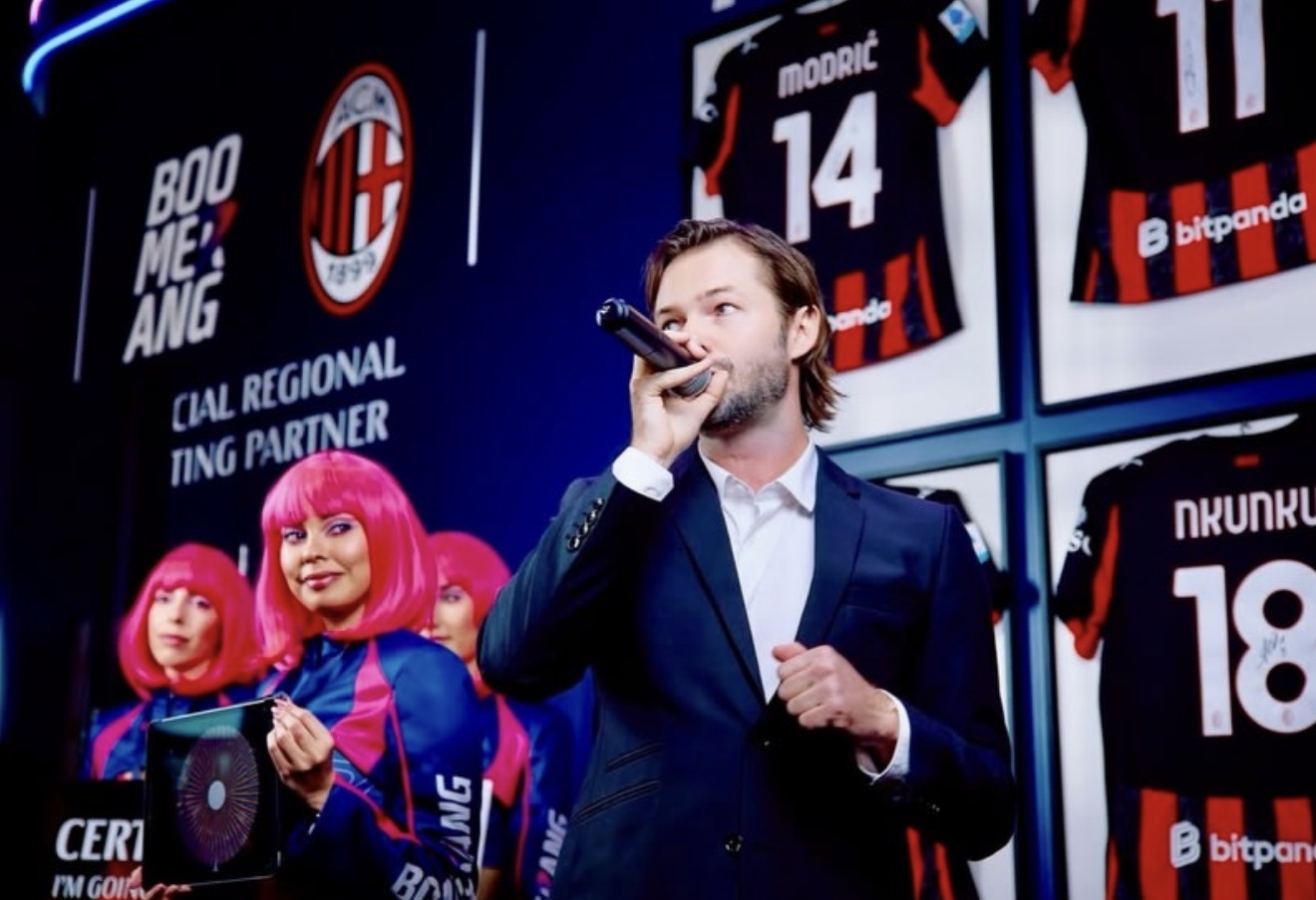 Presenter with a microphone and activation team at an ICE Barcelona exhibition booth