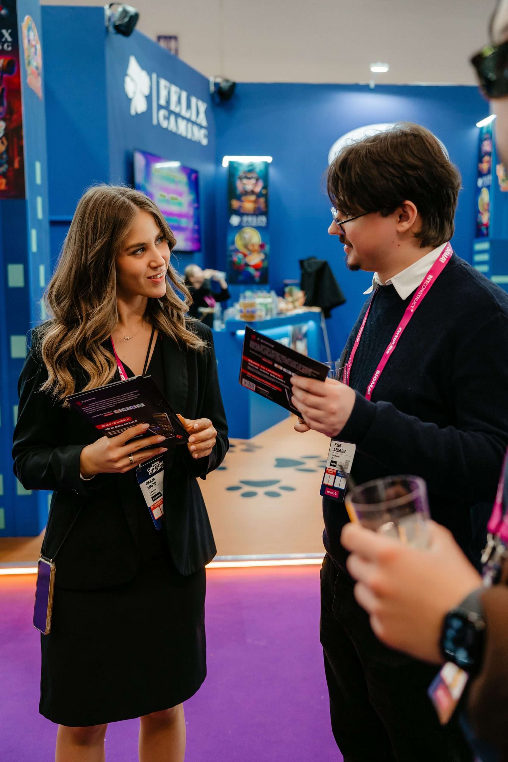 Hostess talking with a visitor and showing brochures at a trade show booth
